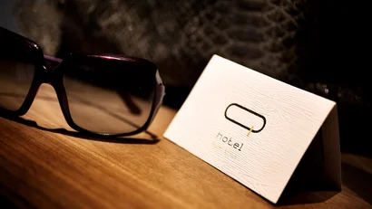 Occhiali da sole su tavolo accanto a biglietto da visita di hotel