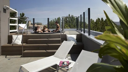 Quattro persone rilassate in una vasca idromassaggio sul terrazzo con lettini