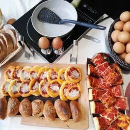 Colazione con pane, mini pizze, focaccine, uova e padella da cucina